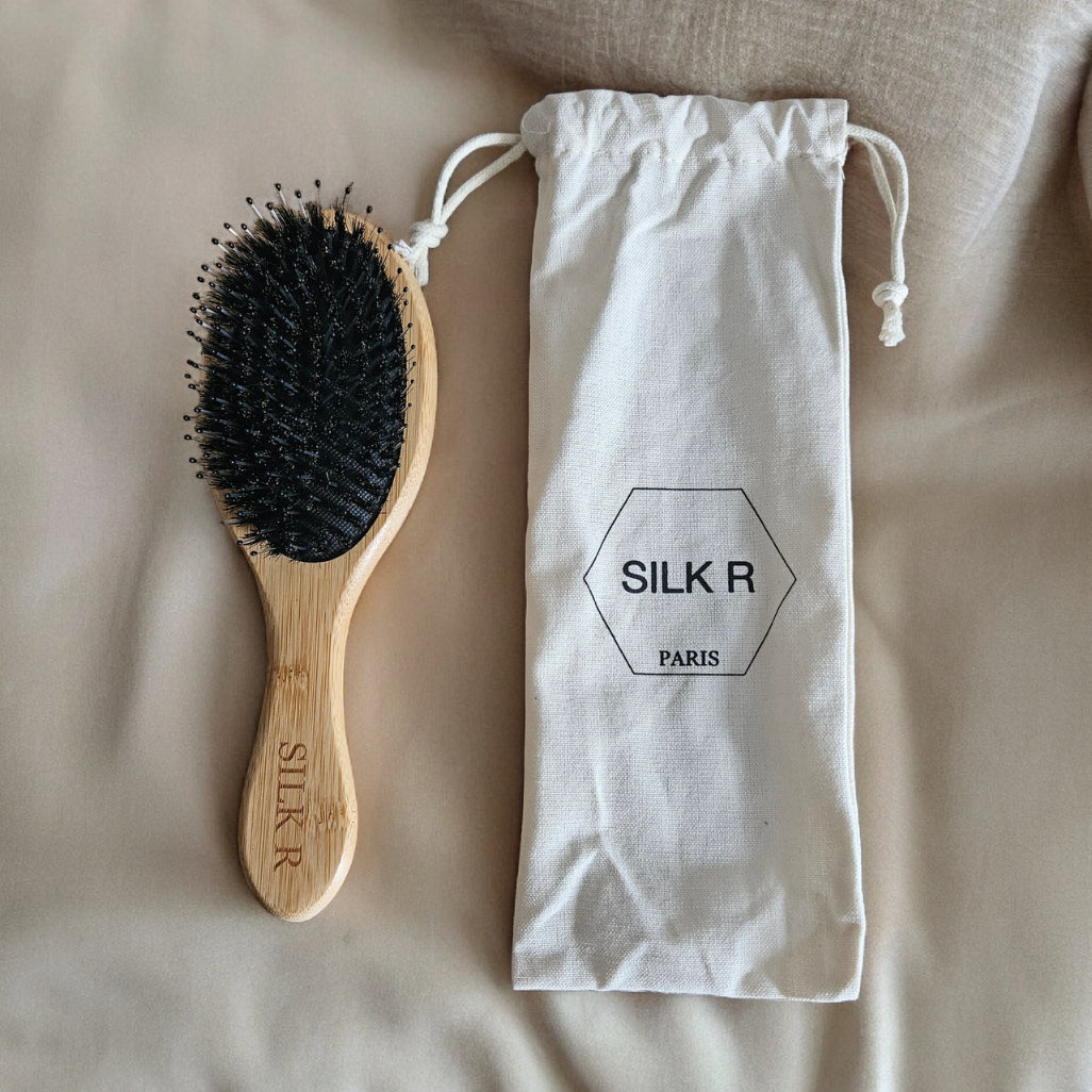 Brosse à poils de sanglier et nylons avac manche en bambou et son pochon en coton biologique posé sur un fond beige