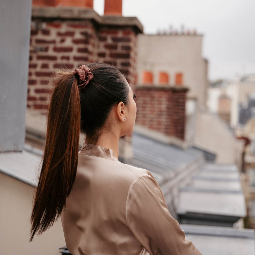 Femme qui pose de dos avec les cheveux attaché avec un chouchou en soie de couleur marron