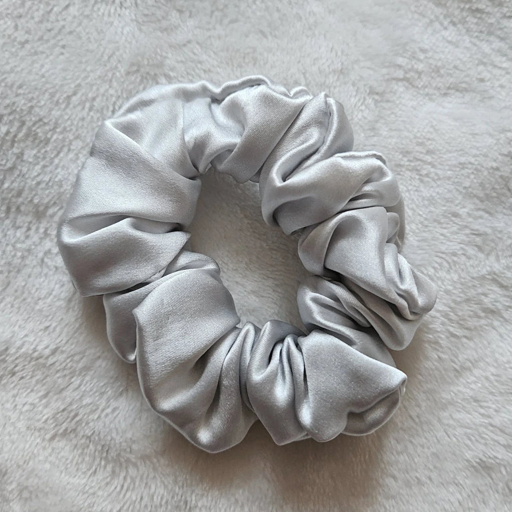 chouchou de couleur gris clair posé sur un fond blanc