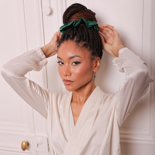 Femme qui pose avec un chouchou de couleur vert foncé attaché en chignon avec des braids